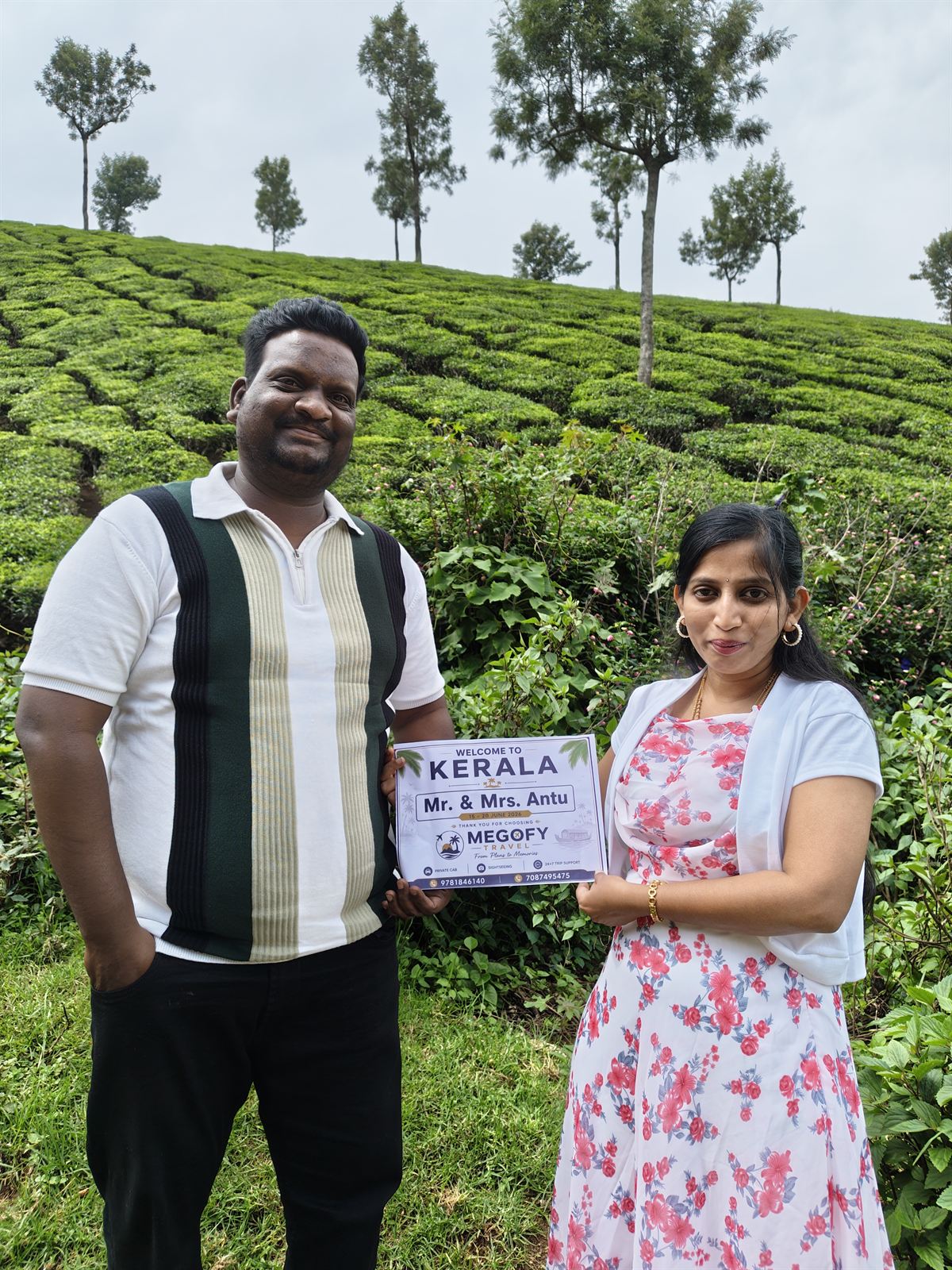 A couple holding a Megofy welcome board in the Munnar tea gardens