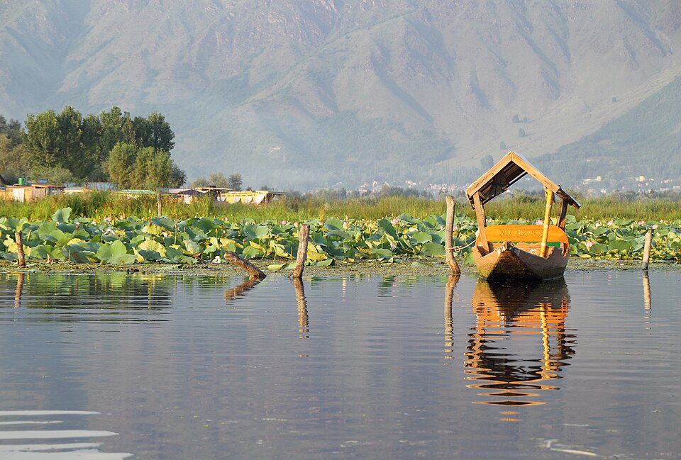 A wooden boat on still water below green hills
